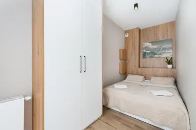 a small bedroom with a bed with a wooden headboard at Krakowiak Apartment 65 in Kraków