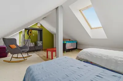 a attic bedroom with a bed and a chair at Bronowice - large and modern apartment with free parking spot in Kraków