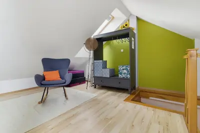 a living room with a chair and a green wall at Bronowice - large and modern apartment with free parking spot in Kraków