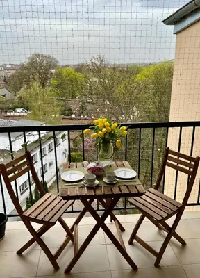 a table with two chairs and a vase of flowers on a balcony at FeelHome Apartment with kitchen in Kraków