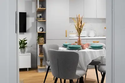 a dining room table with chairs and a white kitchen at Kraków Central Comfort Apartments by Rentujemy in Kraków