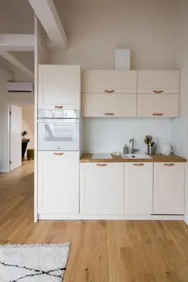 a white kitchen with white cabinets and a wooden floor at Charming apartment in perfect location in Kraków