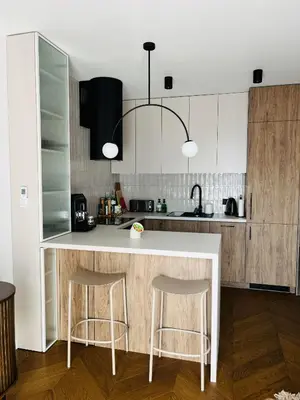 a kitchen with a white counter and two bar stools at Apartament BonHaus Grzegórzecka in Kraków
