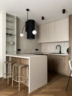 a kitchen with white cabinets and a counter with stools at Apartament BonHaus Grzegórzecka in Kraków