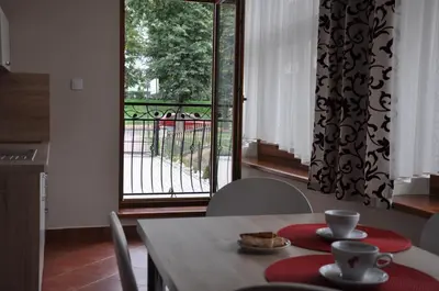a dining room table with a view of a balcony at Apartamenty Lawenda in Rabka
