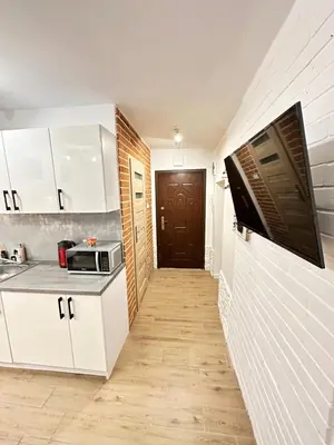 a kitchen with white cabinets and a hallway with a door at Apartment Family Dreams Old Town in Kraków