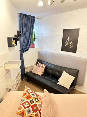 a living room with a black leather couch at Apartment Family Dreams Old Town in Kraków