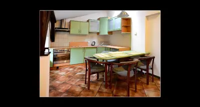 a kitchen with green cabinets and a table and chairs at 777 Apartments 2 in Kraków