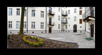 a large white building with a tree in a courtyard at 777 Apartments 2 in Kraków