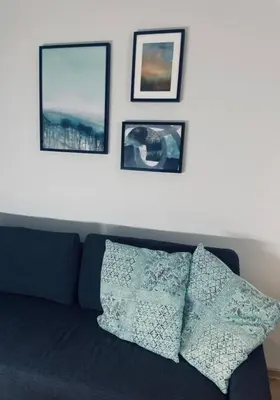 a black couch with three pictures on the wall at MR HOME APARTMENTS - Nullo in Kraków