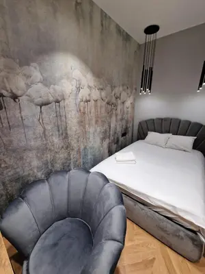 a bedroom with a bed and a chair at Apartamenty Sebastiana in Kraków