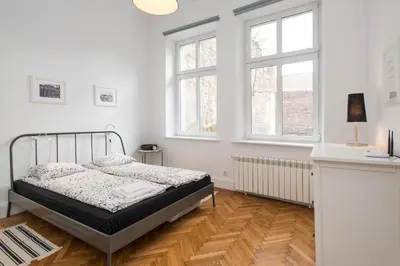a white bedroom with a bed and two windows at Krakow 25 Old Town Apartament in Kraków