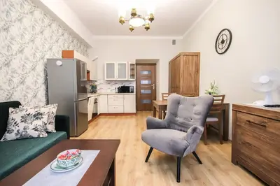 a living room with a green couch and a kitchen at Piękny apartament w centrum Krakowskiego Kazimierza in Kraków
