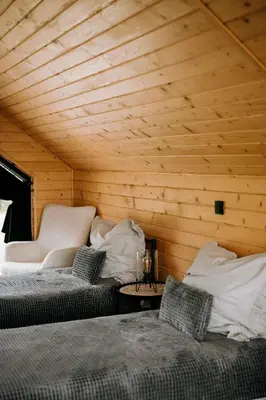 two beds in a room with wooden walls at ArtHouse Podhale in Klikuszowa
