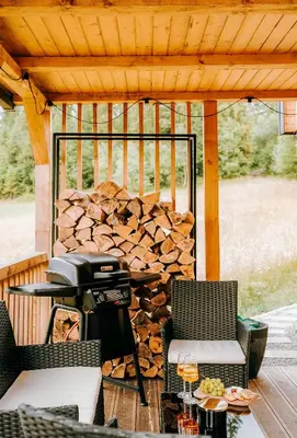 a grill on a patio with a pile of fire wood at ArtHouse Podhale in Klikuszowa