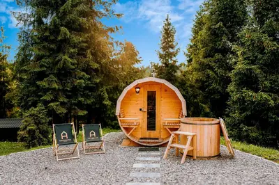 a small wooden cabin with two chairs and a barrel at ArtHouse Podhale in Klikuszowa