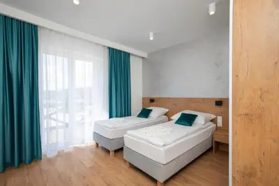 two beds in a room with green curtains at Gorczański Zakątek Jacuzzi & Sauna in Niedźwiedź
