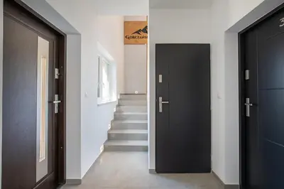 a hallway with two black doors and a staircase at Gorczański Zakątek Jacuzzi & Sauna in Niedźwiedź