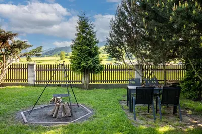 a fire pit in a yard with a table and a fence at Gorczański Zakątek Jacuzzi & Sauna in Niedźwiedź