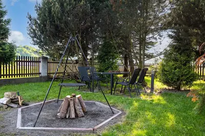 a fire pit in a yard with a table and chairs at Gorczański Zakątek Jacuzzi & Sauna in Niedźwiedź