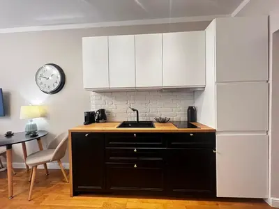 a kitchen with black and white cabinets and a clock at Centrum Apartamenty Stare Miasto in Kraków
