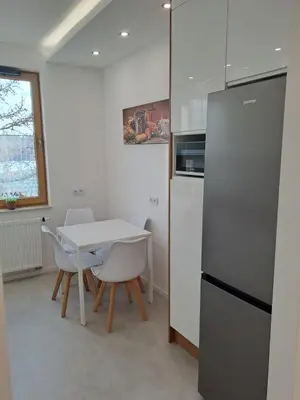 a kitchen with a white table and a refrigerator at Apartamenty Orawska 14 HEMMA in Kraków