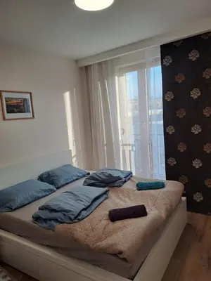 a bedroom with a bed with blue pillows and a window at Apartamenty Orawska 14 HEMMA in Kraków