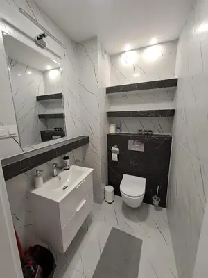 a white bathroom with a sink and a toilet at Apartamenty Orawska 14 HEMMA in Kraków