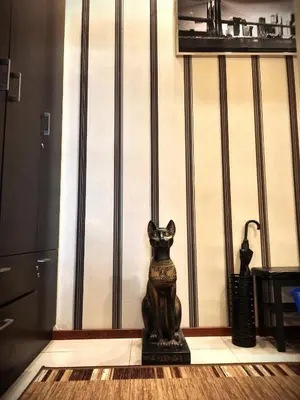 a statue of a cat sitting on a floor next to a wall at Luxury Senate Apartment in Kraków