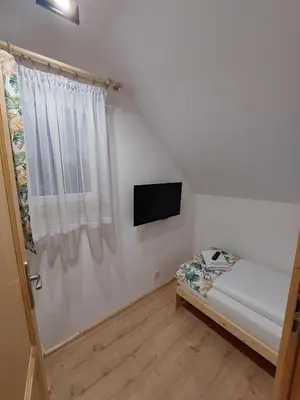 a small bedroom with a bed and a television at Skalne Rancho - BALIA, MASAŻ in Rabka-Zdroj