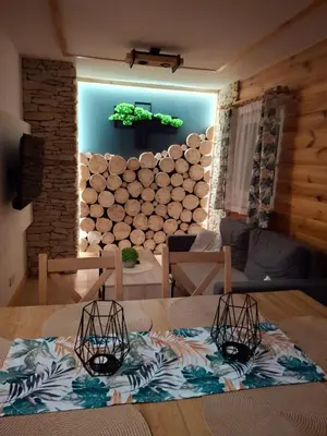 a living room with a table and a wall of logs at Skalne Rancho - BALIA, MASAŻ in Rabka-Zdroj