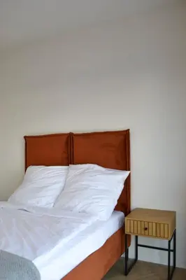 a bed with white sheets and a wooden headboard and a table at Tutu Kraków in Kraków
