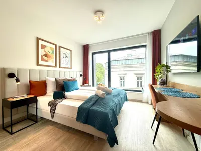 a bedroom with a bed and a table and a window at PANORAMA VIEW by MINT APARTMENT in Kraków