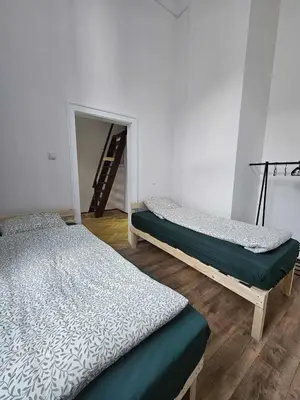 two beds sitting in a room with a staircase at Cozy studio in Cracow in Kraków