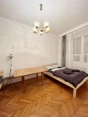 a bedroom with a bed and a table and a chandelier at Cozy studio in Cracow in Kraków