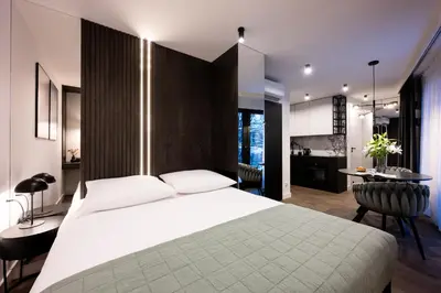 a bedroom with a large white bed and a kitchen at Native Apartments Kościuszki 39 in Kraków