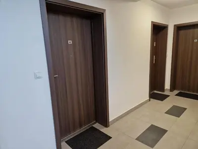a hallway with two brown doors and a tile floor at Apartament Sunray in Kraków