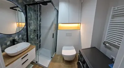 a bathroom with a sink and a toilet and a shower at Apartament Sunray in Kraków