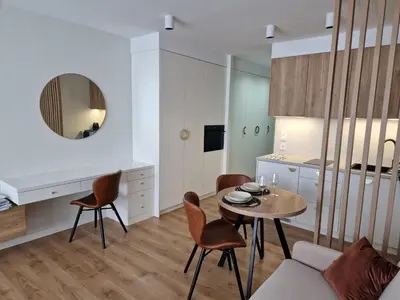 a living room with a table and chairs and a kitchen at Apartament Sunray in Kraków