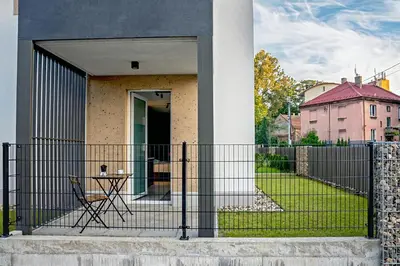 a fence with a chair in front of a house at UR4N Apartment - Heltmana in Kraków
