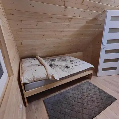 a bed in a room with a wooden wall at beskid.house2 in Spytkowice