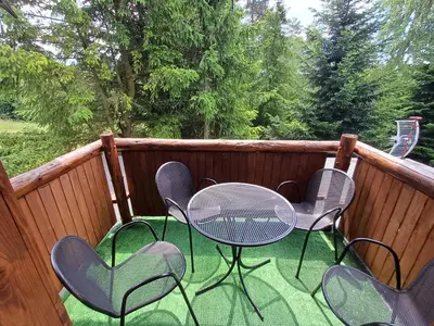 a patio with chairs and a table on a deck at Willa na Bani - apartamenty i pokoje in Rabka