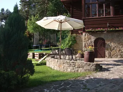 a patio with chairs and an umbrella in front of a house at Willa na Bani - apartamenty i pokoje in Rabka