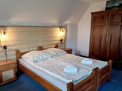 a bedroom with a large bed with a wooden headboard at Willa na Bani - apartamenty i pokoje in Rabka