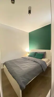 a bedroom with a bed with a green wall at Apartament Złocień in Kraków