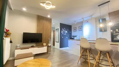 a living room with a television and two bar stools at Apartament Złocień in Kraków