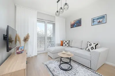 a white living room with a couch and a table at Bright Apartment Park Lotników Near Tauron Arena Kraków by Noclegi Renters in Kraków