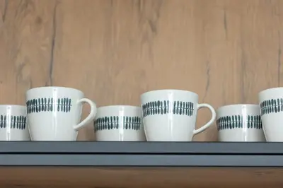 a row of coffee cups sitting on a shelf at Bright Apartment Park Lotników Near Tauron Arena Kraków by Noclegi Renters in Kraków