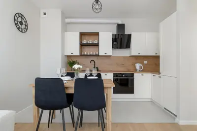 a kitchen and dining room with a wooden table and chairs at Bright Apartment Park Lotników Near Tauron Arena Kraków by Noclegi Renters in Kraków