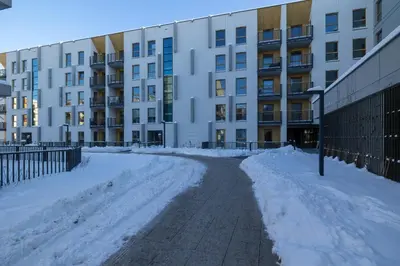 a snow covered street in front of a building at Bright Apartment Park Lotników Near Tauron Arena Kraków by Noclegi Renters in Kraków